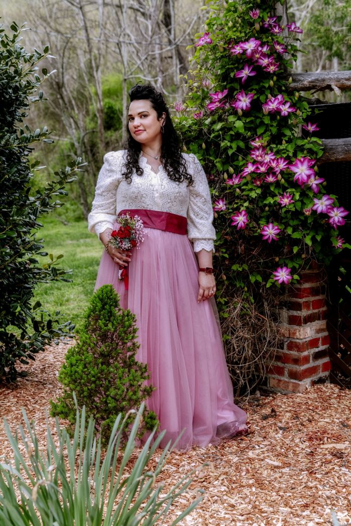 Bride in a blush gown beside a flowering garden wall in Nashville
