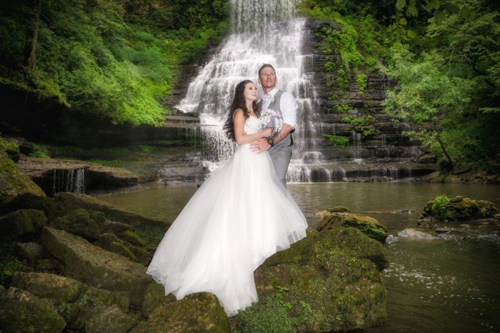 Bride and groom embrace at Carmac Falls waterfall near Nashville