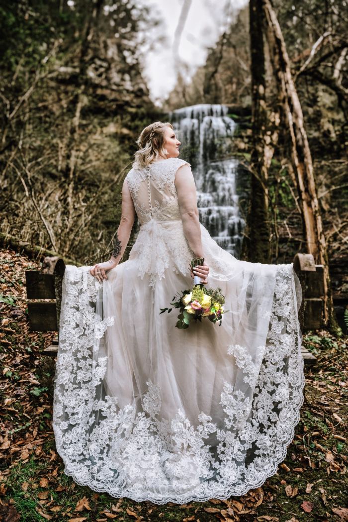 Bride in a lace gown beside a private waterfall near Nashville