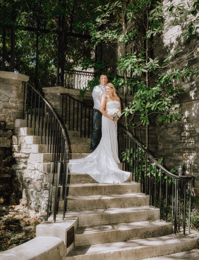 Bride on a stone garden staircase surrounded by greenery