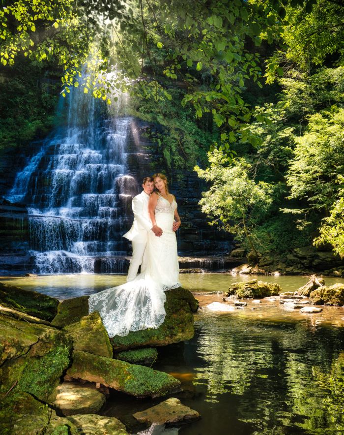 Couple beside a waterfall and creek at an Evins Mill elopement