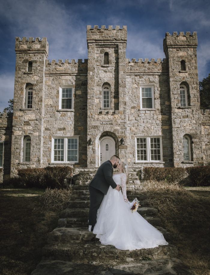 Couple kiss in front of a castle wedding venue near Nashville
